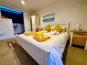 a bedroom with a large white bed with yellow pillows at La Hacienda in uMhlali