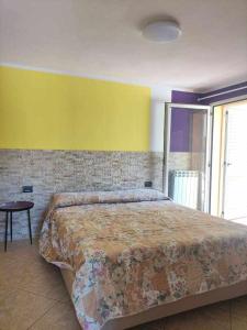 een slaapkamer met een groot bed en een gele muur bij Portu Hill Apartments in Àrbatax