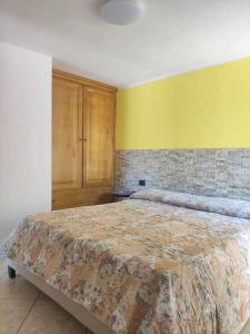 een slaapkamer met een groot bed en een gele muur bij Portu Hill Apartments in Àrbatax
