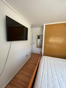 Habitación con cama y TV de pantalla plana en la pared. en Exclusivo y cómodo departamento, en Copiapó