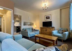 a living room with blue couches and a tv at Luxury 4 Bedroom Seaside Apartment - Glan Y Werydd House in Barmouth