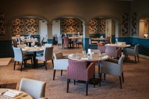 un comedor con mesas, sillas y mesa de comedor en Stoke By Nayland Hotel, Golf & Spa, en Leavenheath