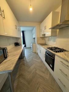 a kitchen with white cabinets and a stove top oven at Smart ROOMS Easy access to Central London By Piccadilly Line in New Southgate