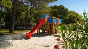 einen Spielplatz in einem Park mit einer roten Rutsche in der Unterkunft Easyatent Safari tent Zelena Laguna in Poreč