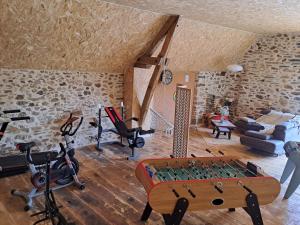 a gym with a ping pong table and exercise equipment at La Clé Du Maumont in Sainte-Féréole