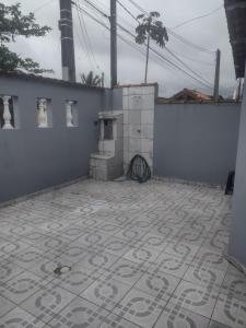 a patio with a tile floor and a wall with a stove at Casa perto da praia mobiliada in Itanhaém