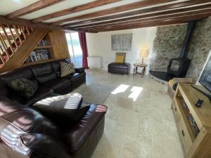 The Granary Stunning Barn Conversion في Broadwoodkelly: غرفة معيشة مع أريكة جلدية وتلفزيون