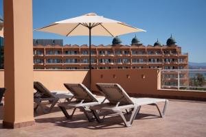 three lounge chairs and an umbrella on a roof at ALEGRIA Colonial Mar in Roquetas de Mar
