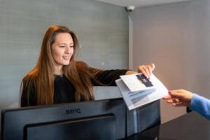 a woman is handing a piece of paper over a television at Stoke By Nayland Hotel, Golf & Spa in Leavenheath +30 photos