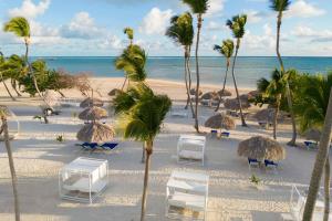 uma praia com cadeiras e palmeiras e o oceano em Serenade Punta Cana Beach & Spa Resort em Punta Cana