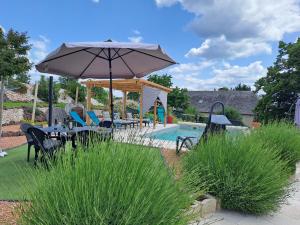 a patio with an umbrella and chairs and a pool at La Clé Du Maumont in Sainte-Féréole
