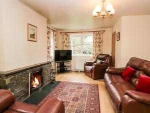 a living room with leather furniture and a fireplace at Thwaite How in Keswick