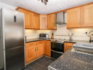 a kitchen with wooden cabinets and a stainless steel refrigerator at Thwaite How in Keswick