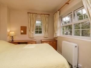 a bedroom with a white bed and two windows at Thwaite How in Keswick