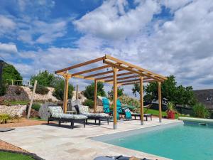 a wooden pergola next to a swimming pool at La Clé Du Maumont in Sainte-Féréole