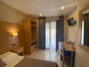 Habitación de hotel con cama, escritorio y ventana en Hotel Cantón, en Barcelona