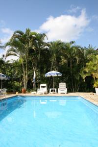 a swimming pool with two chairs and an umbrella at Apartamentos Atobá Flats in Juquei