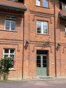 - un bâtiment en briques avec une porte et des fenêtres vertes dans l'établissement Ferienwohnungen im Haus Waldstück, à Lärz