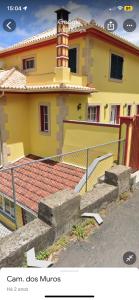 um edifício com uma cerca e escadas em frente em caminho da praia da maiata em Porto da Cruz