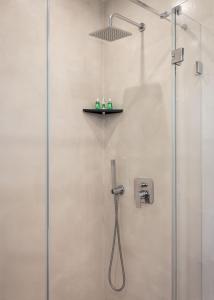 a shower with a glass door and a shelf on the wall at Athenian Riviera Executive Apartment in Vari