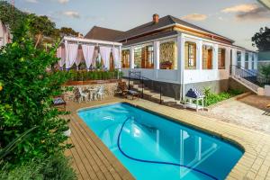 a home with a swimming pool and a house at Ravenscliff White House in Oudtshoorn