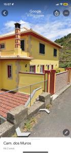 une maison jaune avec une clôture devant elle dans l'établissement caminho da praia da maiata, à Porto da Cruz