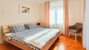 um quarto com uma cama, uma cadeira e uma janela em FilinHome Jaksica Suite em Novi Sad
