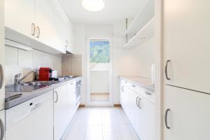 uma cozinha branca com armários brancos e uma janela em Nice apartment ideally located in Martigny em Martigny-Ville
