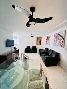 a living room with a couch and a ceiling fan at Frente ao mar Pitangueiras - 3 suítes in Guarujá