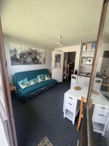 a living room with a blue couch and a table at Studio tout confort in Les Adrets