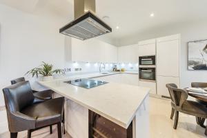 a kitchen with a island with a sink and chairs at Palace Wharf in London