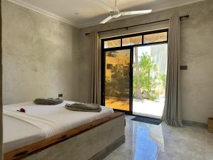 a bedroom with a bed and a large window at Jambo Beach Hotel Paje in Paje