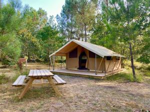 een tent met een picknicktafel ervoor bij Camping la Kahute, tente lodge au coeur de la forêt in Carcans