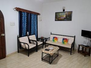 sala de estar con sillas, mesa y TV en Brittos Homestay en Mandrem