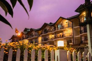 a building with a fence and flowers in front of it at Kapri Luxury Apartment in Nuwara Eliya