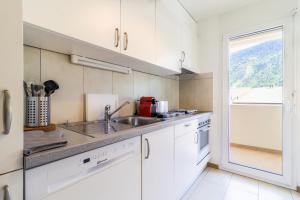 a kitchen with white cabinets and a sink and a window at Nice apartment ideally located in Martigny in Martigny-Ville