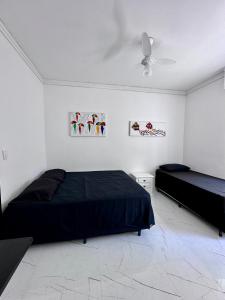een slaapkamer met 2 bedden en een plafondventilator bij Frente ao mar Pitangueiras - 3 suítes in Guarujá