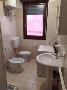 ein Bad mit einem Waschbecken, einem WC und einem Fenster in der Unterkunft Residence Corallo in Rosolina Mare
