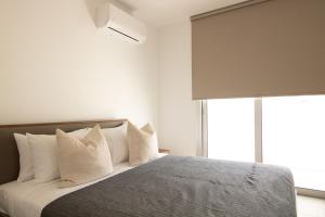 een slaapkamer met een bed met witte lakens en kussens bij Phaedrus Living Coral Suites Aura in Larnaka