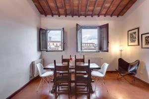 - une salle à manger avec une table, des chaises et 2 fenêtres dans l'établissement Mamo Florence - Opera - Sinfonia - Minuetto - Melody Apartments, à Florence