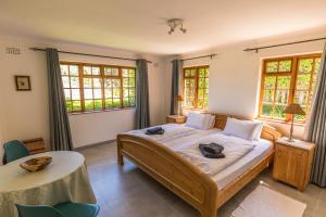 a bedroom with a bed and a table and windows at Hout Bay Lodge in Hout Bay