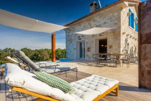 a patio with a bunch of chairs and an umbrella at Rustic villa Krug with panorama view in Buje in Bibali