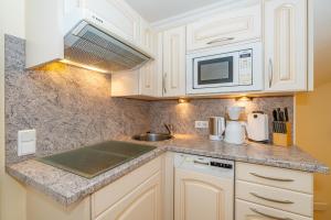 a kitchen with white cabinets and a sink and a microwave at Westerhörn 46 15 in Keitum +8 photos