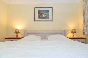 a bedroom with a white bed with two lamps at Westerhörn 46 15 in Keitum