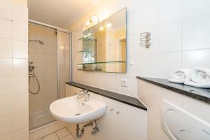a white bathroom with a sink and a shower at Westerhörn 46 15 in Keitum