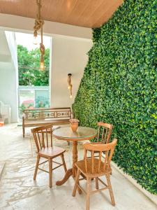 a table and chairs in front of a green wall at Pousada do Porto Mar in Pôrto de Pedras