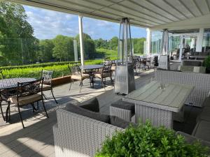 un patio cubierto con mesas, sillas, mesas y sillas en Stoke By Nayland Hotel, Golf & Spa, en Leavenheath