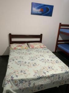 a bedroom with a bed with a floral bedspread at POUSADA YHWH (Pedro & Neth) in Araruama