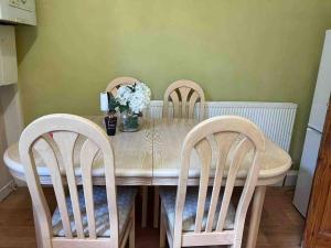 a dining room table with two chairs and a vase of flowers at Cosy 2 Bed House in Rochdale in Rochdale