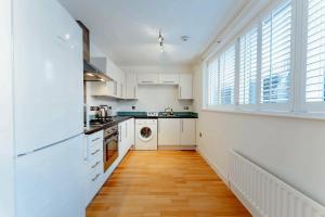 een keuken met witte kasten en een houten vloer bij Brick Lane & Shoreditch London Apartment in Londen